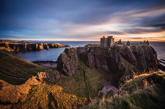 Dunotter castle at sunset. A castle on a cliff next to the sea